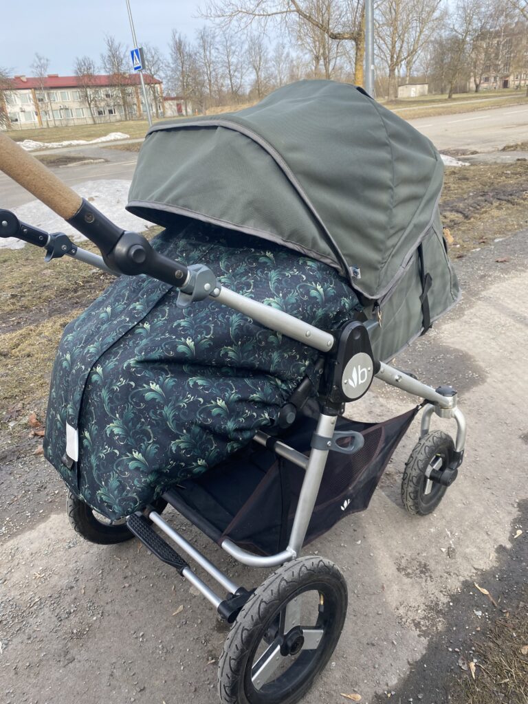 Lapsevaker seisab teel ja sel on tumesiine roheliste lehtedega jalakate.