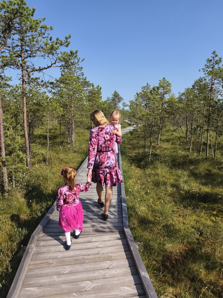 Ema ja tütar roosade kleitidega rabas laudteel.