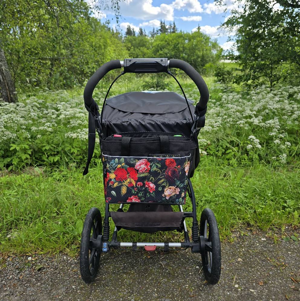 Lapsevanker, millel on vankrikott, seisab teel. Taustal on roheline muru ja rohelised puud.
